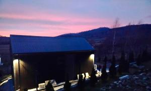 a building with a blue roof with a mountain in the background at Domek Pośród Gór - JACUZZI WLICZONE W CENIE POBYTU,bajeczne widoki, relax i spokój in Laski