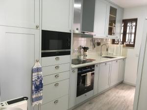 a kitchen with white cabinets and a sink and a stove at Maresia in Sines