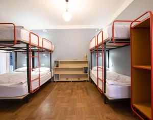 a room with three bunk beds and a wooden floor at Ruby Hostel, Kutaisi - Private & Shared Rooms in Kutaisi