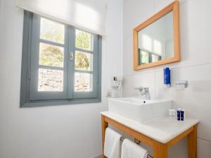 a bathroom with a sink and a mirror at White Suites Resort- Adults Only Hotel in Afitos