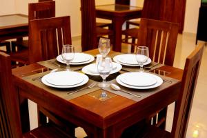 a wooden table with plates and wine glasses on it at Ayana Resort Wilpattu in Wilpattu +44 photos