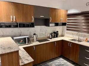 a kitchen with wooden cabinets and marble counter tops at Saadatus Apartment in Kaduna