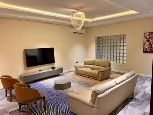 a living room with a couch and a flat screen tv at Saadatus Apartment in Kaduna