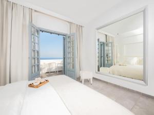a white bedroom with a large mirror and a bed at White Suites Resort- Adults Only Hotel in Afitos