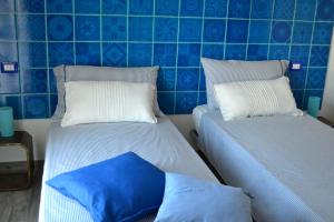two beds in a room with blue tiled walls at B&B La Casa Bianca di Porto Conte in Porto Conte
