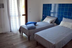 a bedroom with two beds and a blue tiled wall at B&B La Casa Bianca di Porto Conte in Porto Conte