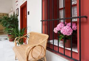 a wicker chair and a vase of pink flowers on a balcony at Sercotel Las Casas de los Mercaderes in Seville +37 photos