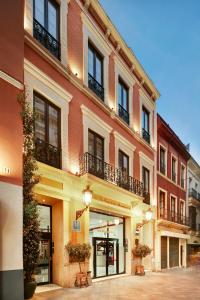 a tall red brick building with balconies on a street at Sercotel Las Casas de los Mercaderes in Seville
