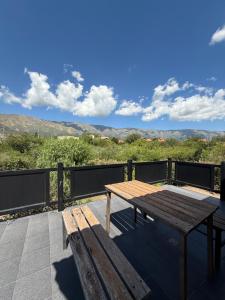 a wooden table and bench on a balcony with mountains at Chalet Individual Maiten 1 in Merlo