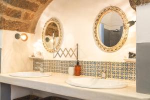 two sinks in a bathroom with two mirrors at Dammuso del Nonno in Pantelleria +33 photos