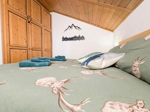 a bed with a green comforter with animals on it at Begar Nest - ski slope front and panoramic in Sappada