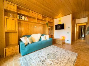 a living room with a blue couch and a tv at Begar Nest - ski slope front and panoramic in Sappada