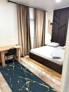 a bedroom with a bed and a table and a desk at Adel in Almaty