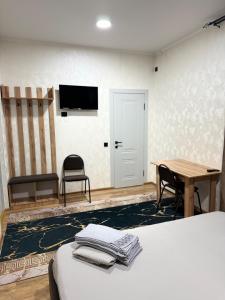 a room with a bed and a table and a tv at Adel in Almaty +11 photos