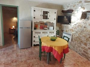 a kitchen with a yellow table with chairs and a refrigerator at Gîte Côté Sud in Vagnas