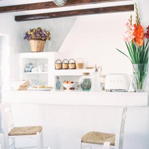 a white counter with two chairs and flowers on it at Aether Boutique Stay in Mikonos