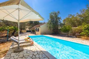 an umbrella and a chair next to a swimming pool at Villa Old Vineyard in Kontogiannátika