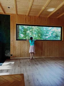 a woman standing in a room looking out a window at Domek Pod Jemiołami - Mały Głęboczek in Mały Głęboczek