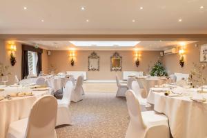 a banquet hall with white tables and white chairs at Banbury Wroxton House Hotel in Banbury