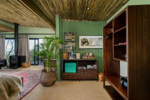 a living room with green walls and a tv at Camp Figtree by The Oyster Collection in Addo