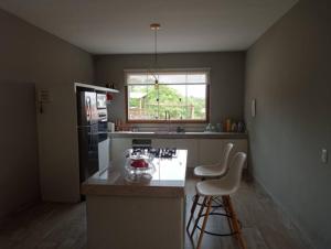 a kitchen with a counter and two bar stools at Sitio Vila Monte Verde in Jaboticatubas