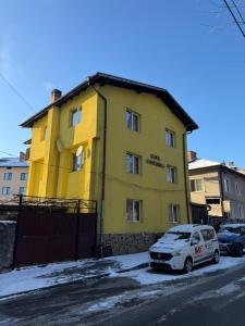 a yellow building with a car parked in front of it at къща Солунови in Dobrinishte
