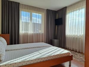 a bedroom with a bed and two large windows at къща Солунови in Dobrinishte