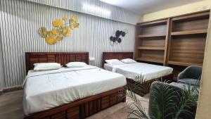 a room with two beds and a chair in it at Amara Homestays in Prayagraj