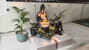 a statue of a buddha sitting on a table with plants at Amara Homestays in Prayagraj