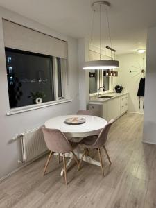 a kitchen and dining room with a white table and chairs at Cozy ocean front apartment in Reykjavík