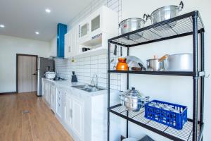 a kitchen with a sink and a shelf with pots and pans at Panmora Poolvilla Sattahip in Ban Tao Than