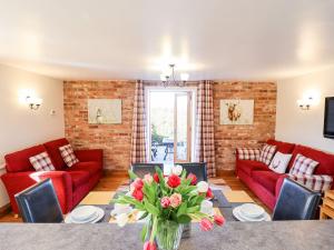 a living room with red couches and a table with flowers at The Mill House in Louth