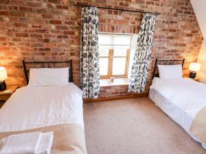 two beds in a room with a brick wall at The Mill House in Louth