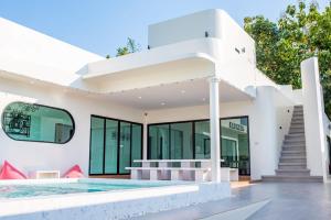 a white house with a swimming pool and stairs at Panmora Poolvilla Sattahip in Ban Tao Than