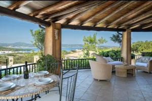 a patio with a table and chairs on a balcony at Orsa sul mare a Baja Sardinia in Cala Bitta