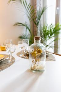 a glass jar with flowers in it on a table with glasses at Grand Studio Centre Fontainebleau INSEAD - Cocon Deluxe in Fontainebleau