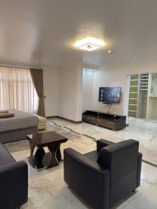 a living room with a couch and a tv at Glovis Suites in Abuja