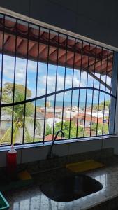 a kitchen window with a sink and a view of the ocean at Hostel Casa da Cida II in Pipa