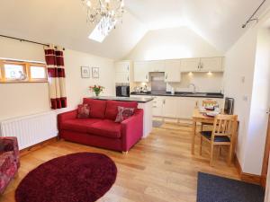 a living room with a red couch and a kitchen at The Stables in Louth