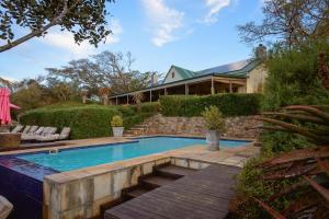 a swimming pool with a wooden deck next to a house at Camp Figtree by The Oyster Collection in Addo