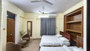 a bedroom with two beds and a ceiling fan at Amara Homestays in Prayagraj +30 photos