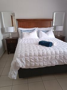 a bed with a white comforter and two lamps at J&B Tuiste in Reebok