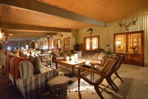 a living room with couches and a table and chairs at Camp Figtree by The Oyster Collection in Addo