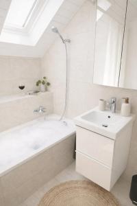 a white bathroom with a tub and a sink at Quiet Forest-Side Apartment in Flamatt +18 photos