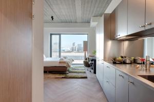 a kitchen with white cabinets and a bed in a room at Makerstoren Short stay serviced apartments for 28 to 180 days in Amsterdam