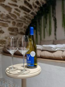 a bottle of wine and two wine glasses on a table at La Voûte Etoilée - Suite avec sauna et jacuzzi in Étoile-sur-Rhône
