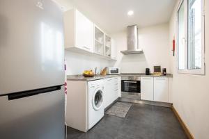 a kitchen with white cabinets and a washer and dryer at Queimada Houses in Funchal