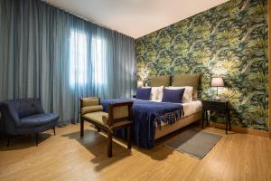 a bedroom with a bed and a chair at Queimada Houses in Funchal