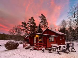 eine kleine rote Hütte im Schnee bei Sonnenuntergang in der Unterkunft Farmstay Götes Cabin, 2p in Årjäng + 20 Fotos