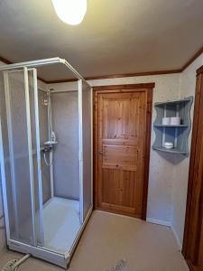ein Badezimmer mit Dusche und Holztür in der Unterkunft Farmstay Götes Cabin, 2p in Årjäng